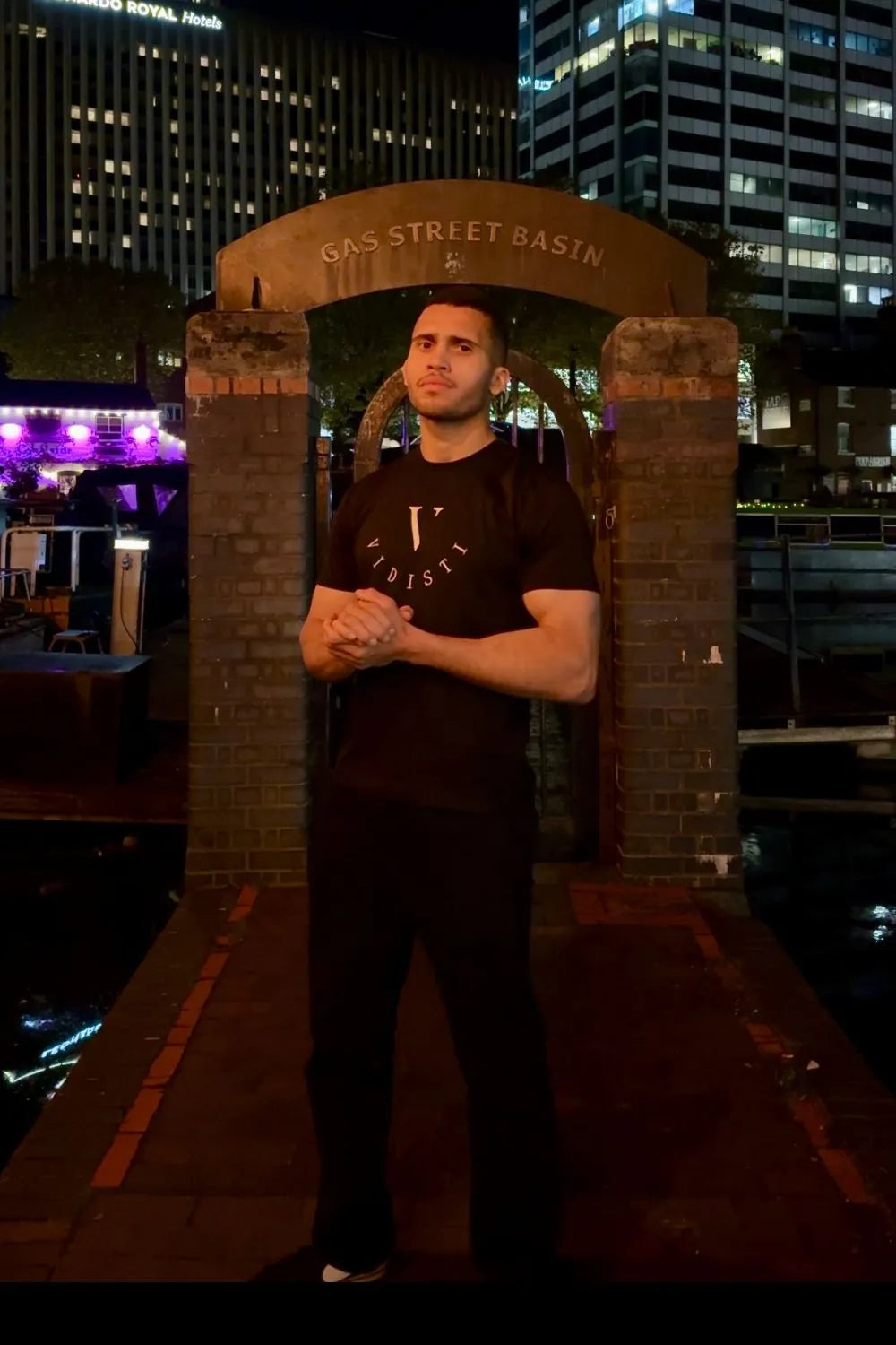 Man standing in front of a brick archway with city lights in the background